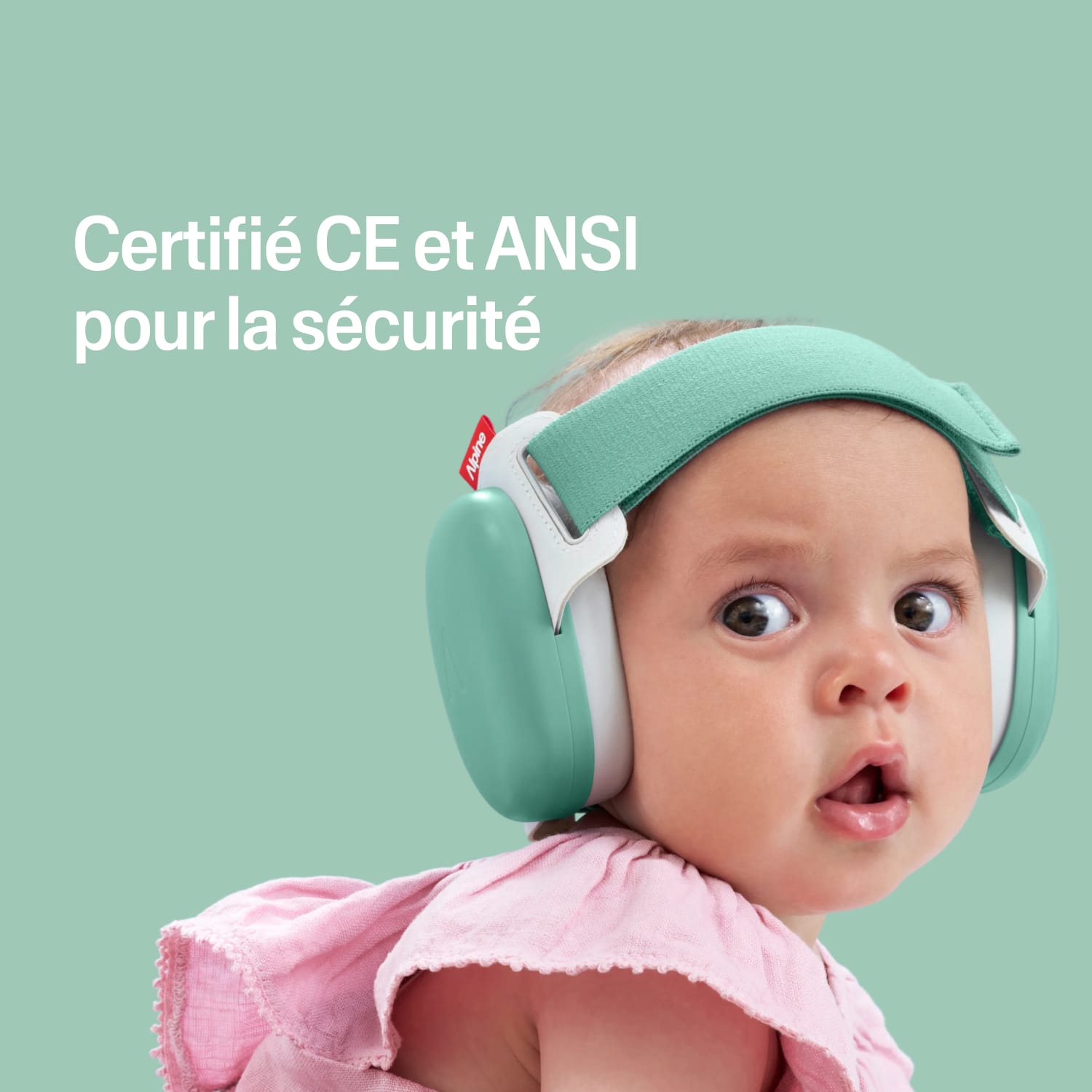 Baby wearing green ear protection with certification text on a light green background 