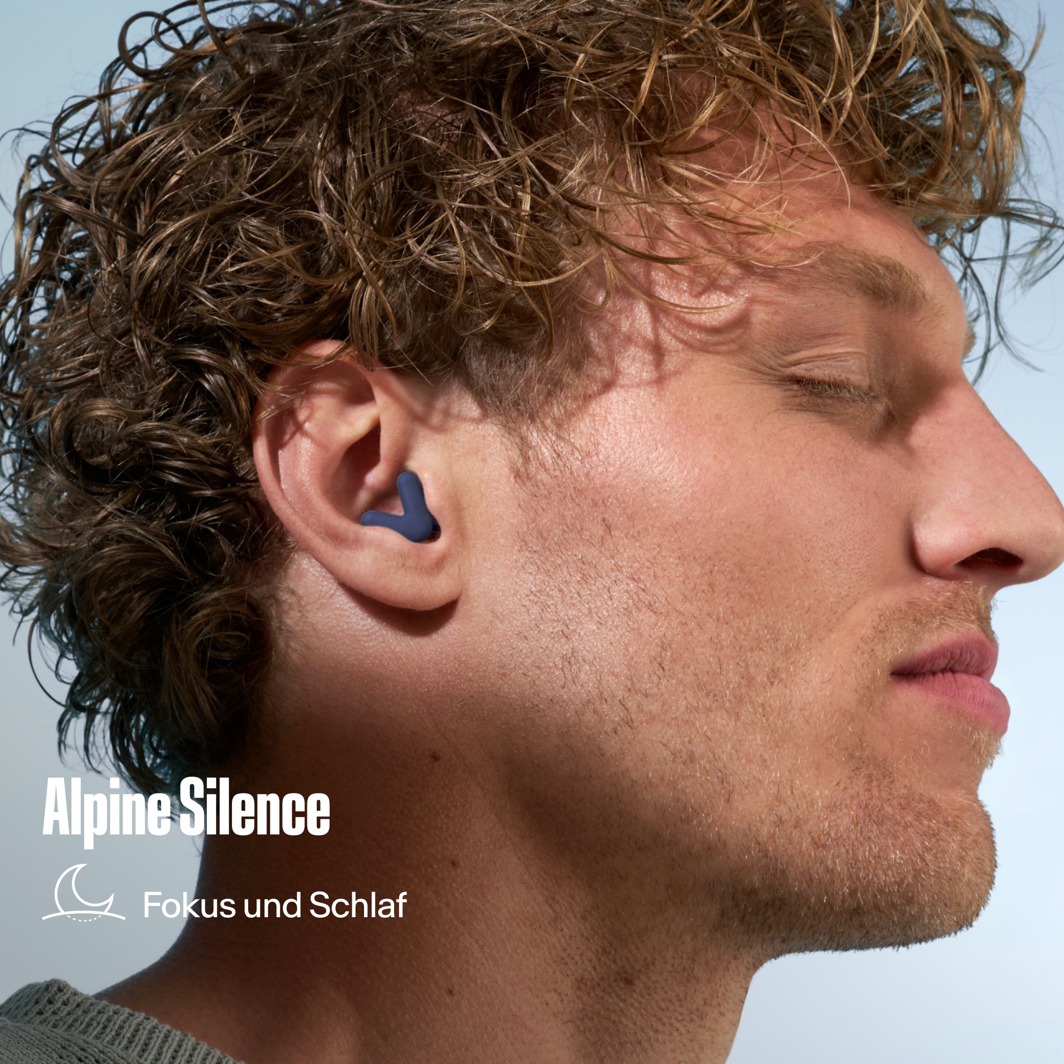 Alpine Silence Ohrstöpsel im Ohr eines Mannes mit lockigem Haar, mit dem Text &